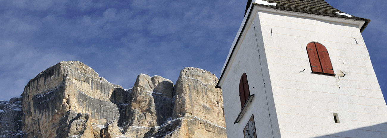Der Glockenturm von St. Leonhard und steinige Berge im Hintergrund
