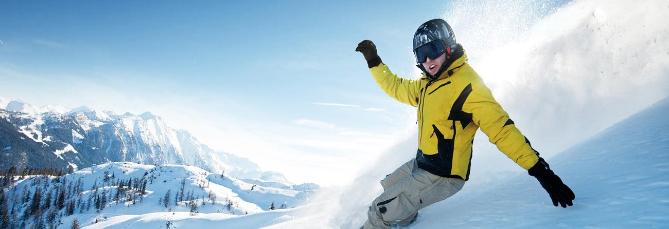 persona su uno snowboard alza la neve mentre fa una curva