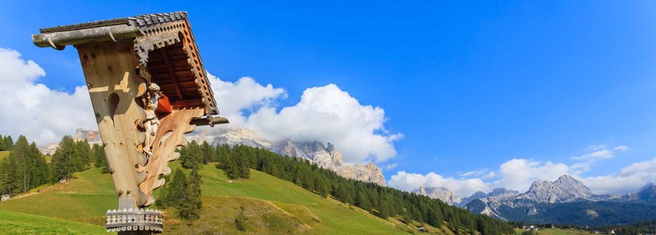 Un capitello di legno a fianco di una strada a San Cassiano