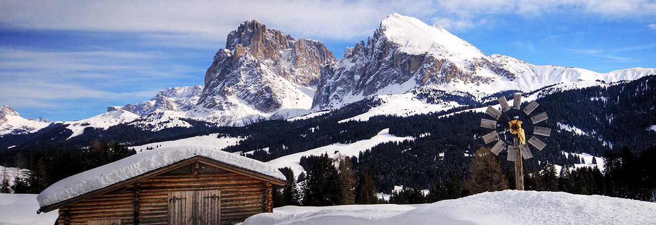 Capanna di legno e ruota segnavento sulla cima di una montagna innevata