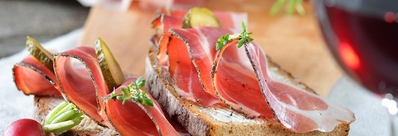 Scheiben dick geschnitter Speck auf der Oberseite eines schwarzen Roggenbrot